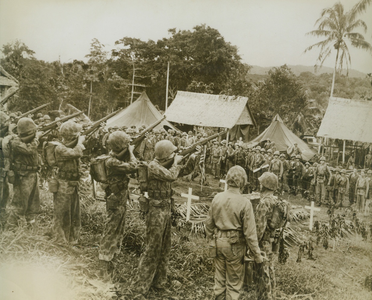 Leathernecks Honor Their Dead, 8/30/1943. New Georgia – Clad in camouflage suits, members of the U.S. Marine Corps pay tribute to buddies who lost their lives in action at Viru Harbor, New Georgia.  In foreground the rifle squad stands ready to blast a salute to the fallen Marines, while a bugler waits to play the final “Taps”. Credit (U.S. Marine Corps photo from ACME);