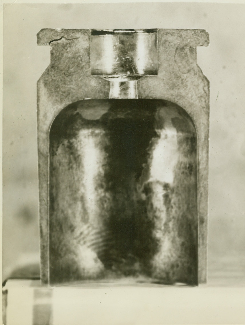 ALLEGEDLY DEFECTIVE, 1/5/1943. ST. LOUIS, MO. – Cartridge case produced at St. Louis Ordnance Plant, showing a crack in upper left corner. Inspectors charge that too large a proportion of these cases are defective. Credit: ACME;