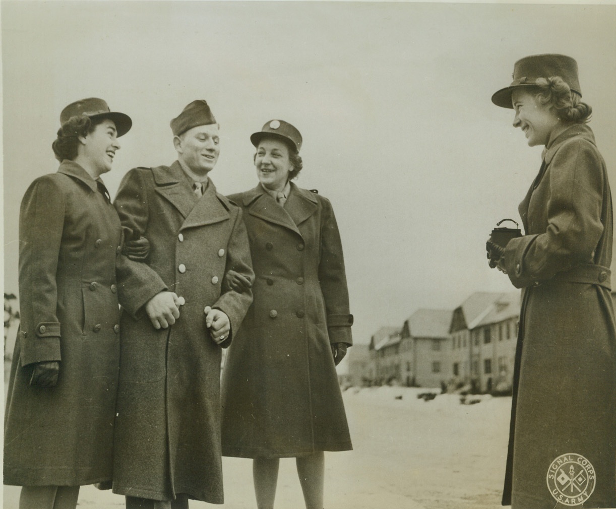 FOR THE FOLKS BACK HOME, 1/3/1943. FORT DEVENS, MASS. – Private Aime Courmier of Westbrook, Me., poses for a photo to send to the folks back home with WAACS Mary Welsh (left) of Vincennes, Ind., and Rebecca Carey of Durham, N.C. Alice Games of Boise, Idaho, takes the picture on the grounds of Fort Devens, where the girls have been assigned to duty. Credit: Signal Corps photo from ACME;