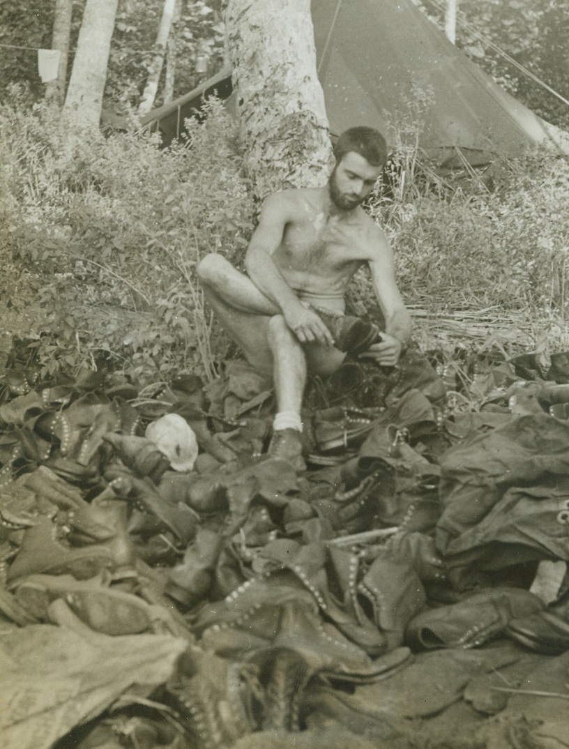 Seek And Ye Shall Find, 1/4/1943. NEW GUINA—SGT. George Brownell of Platterville, Wis., is looking for a pair of shoes in a salvage dump in a native village in New Guinea.  This photo was taken at the start of the American offensive to retake Buna.Credit ACME;