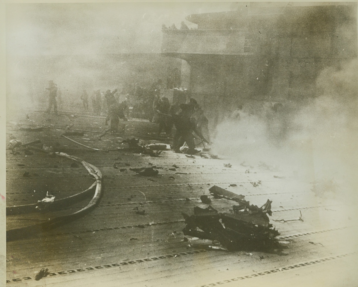After Jap Plane Hit "Hornet's" Deck, 1/12/1943. Crew members of the U.S. aircraft carrier Hornet, battle desperately against long odds to put out a fire started when a Jap bomber suicide-dived into the warship's signal bridge, in this photo released by the Navy in Washington today. Wreckage from the bomber covers the ship's flight deck. Picture was taken during the battle of the Santa Cruz Islands, Oct. 26, 1942, when the carrier was so badly damaged it later had both sunk by other American warships. Credit: (U.S. Navy Photo from ACME);