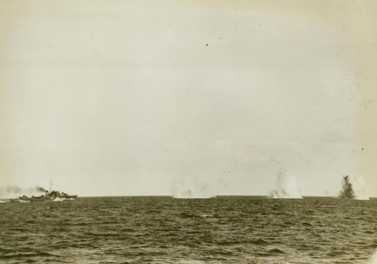 Triple Miss, 1/17/1943. Aboard A Royal Navy Cruiser – An Axis plane, attacking a convoy bound for Malta, misses its target three times, raising triple geysers as the “eggs” hit the water/The “misses” fell short of the destroyer at right of photo. Photo was made aboard a British cruiser that accompanied the convoy. 1/17/43 Credit Line (ACME);