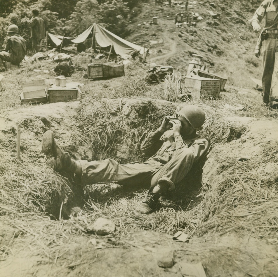 LOOKOUTS, 1/26/1943. GUADALCANAL, S.I.—Lookouts on a hill overlooking Grassy Knoll, 4 miles west of Henderson Field, keep constant watch as the Army launches an offensive on Jap lines, entrenched along the hillside and in the forest below. Latest reports indicate that six important elevations were captured and 110 Japs were killed in the battle. Credit: Acme;