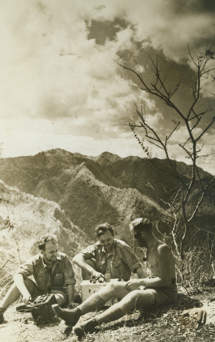 BRAVERY AMAZES HOMELAND, 1/25/1943. TIMOR ISLAND—Three Aussie signal corps men gather ‘round the set they constructed on the Jap-held island of Timor. To show that they were working in the camp of the enemy as guerilla fighters they sent a message to the mainland. Their superiors sent back the message, “What is the Christian name of Jack Sargent’s wife?” The trio of snipers returned the correct answer: “Kathleen” and the contact was established. Credit: Acme;