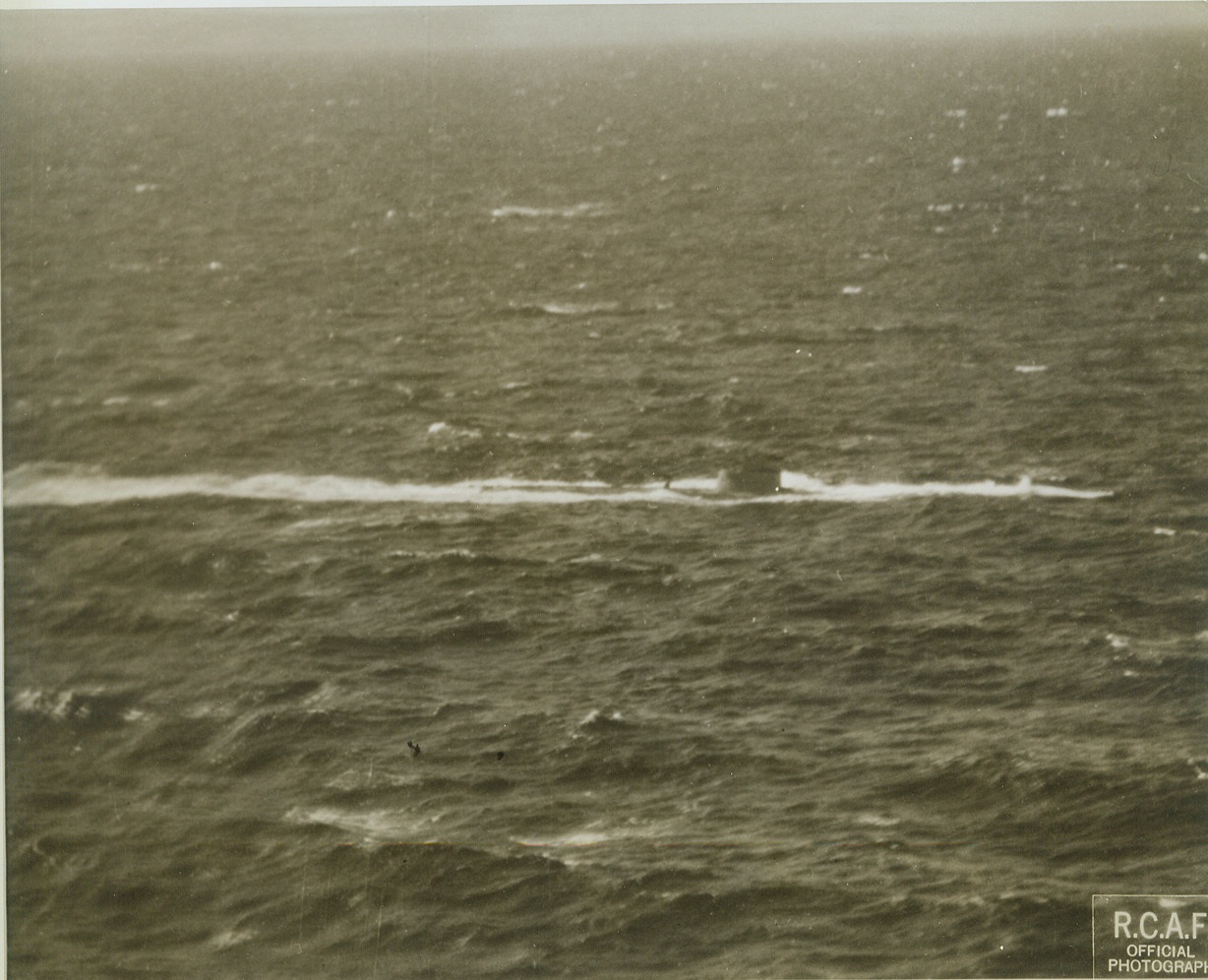 U-Boat Ducks, 1/7/1943. SOMEWHERE IN THE ATLANTIC -- The conning tower and a section of the afterdeck of a Nazi sub can be seen as the U-boat ducks to avoid an attack by an RCAF Atlantic coastal patrol bomber. A few moments later, bullets rattled on its hull and depth charges from the plane churned the water all around it.  Credit: (ACME);
