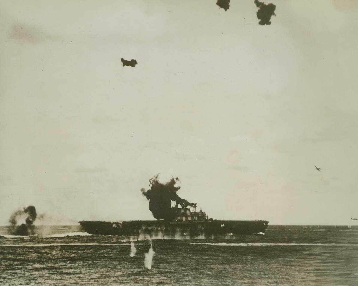 Jap Suicide Dive Catches “Hornet”, 1/12/1943. A huge ball of flame and smoke rises from the spot on the signal bridge of the U.S. Aircraft Carrier Hornet where a Jap bomber crashed after a suicide dive, in this photo released by the Navy Department in Washington today. Note other Nip Torpedo and Dive Bombers circling, (right, in photo). Action took place during the battle of the Santa Cruz Islands, Oct. 26, 1942, in which the carrier was so badly damaged that it was abandoned and the vessel sunk by other American warships. Credit: U.S. Navy photo from ACME;