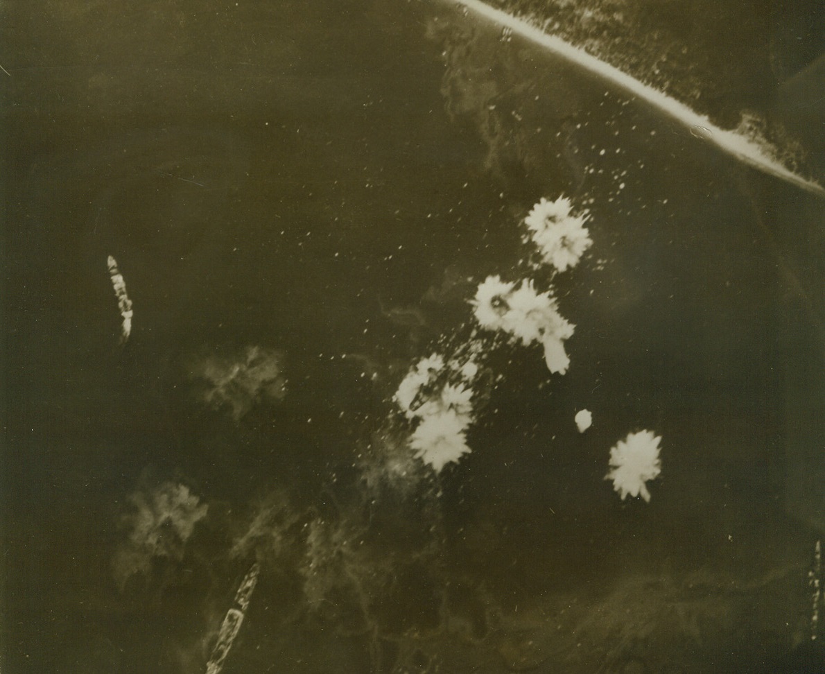 Deadly Flowers, 1/14/1943. Looking like flowers blooming in a garden a cluster of bomb explosions bracket a Jap cargo ship, (center of photo), during a heavy attack by U.S. Army flying fortresses in the Buin sector near the Southeast tip of Bougainville island, in the Solomons last Nov. 18th.  Another cargo vessel, (top left), frantically swings out of the target area, while other Nip ships, (lower right and left) are “cold turkey” for the U.S. Airmen.  This photo, taken by a U.S. Navy cameraman, was released in Washington today. Credit line (U.S. Navy photo from ACME);