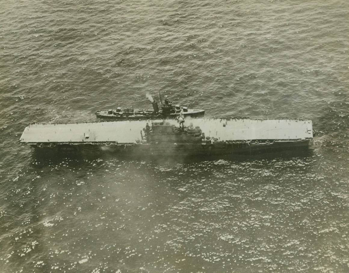 Fourth Carrier Lost in Pacific Battles, 1/12/1943. One of the last photos to be made of the U.S.S. Hornet, aircraft carrier which was sunk during the battle of Santa Cruz islands, Oct.26, 1942, by American surface ships after being severely damaged by two attacks of Japanese bomber and torpedo planes.  The 20,000-ton carrier was commissioned a year ago: her loss announced on Oct. 31, but her identity was not released until Jan. 11, 1943.  A U.S. Destroyer is alongside the stricken ship – the fourth lost in action since outbreak of war in the Pacific. Credit (official navy photo – ACME);
