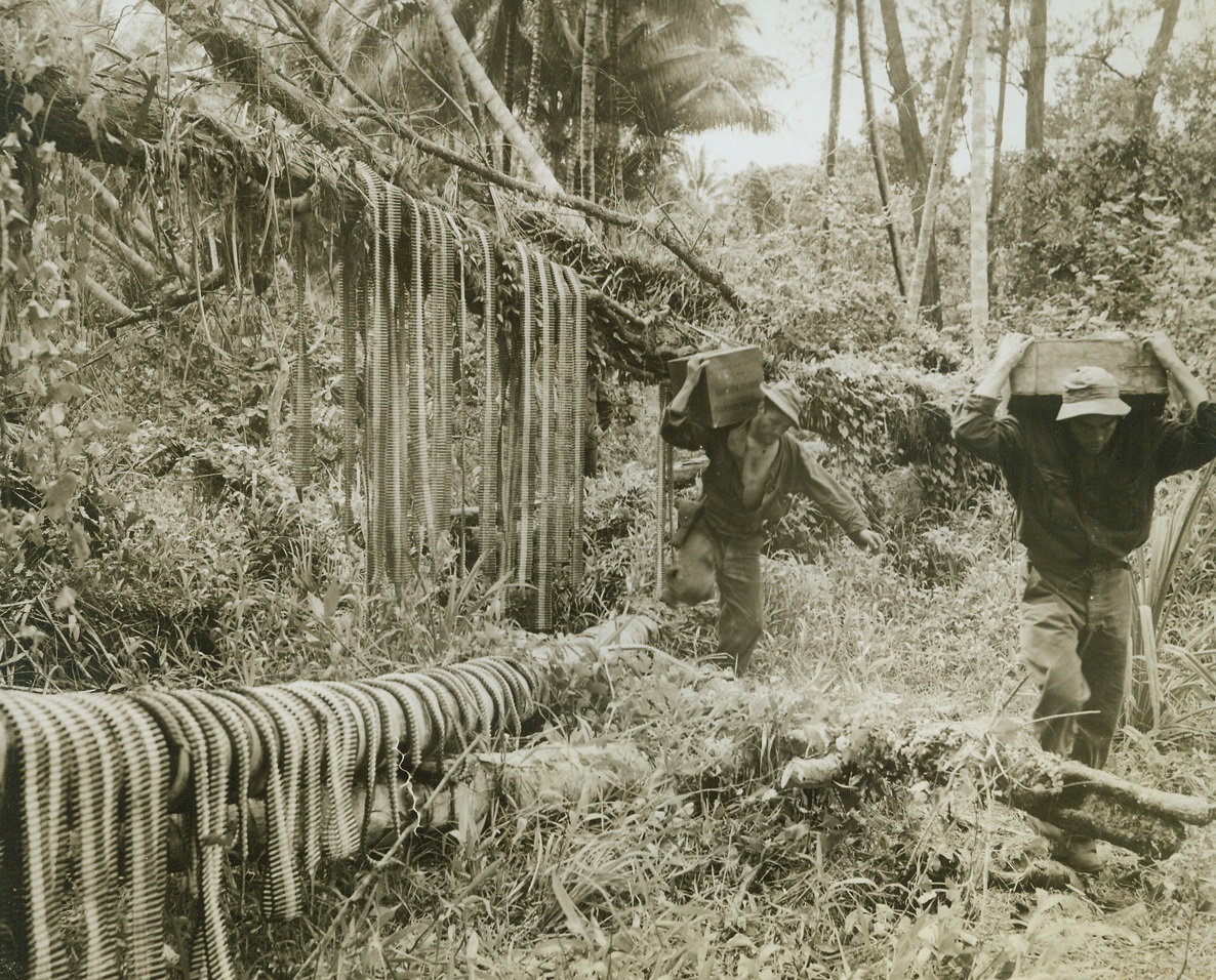 Passing the Ammunition, 1/4/1943. New Guinea – U.S. soldiers carry ammunition up to the front preparatory to the offensive to retake Buna.  Photo was taken at a native village before the campaign. Credit line (ACME);