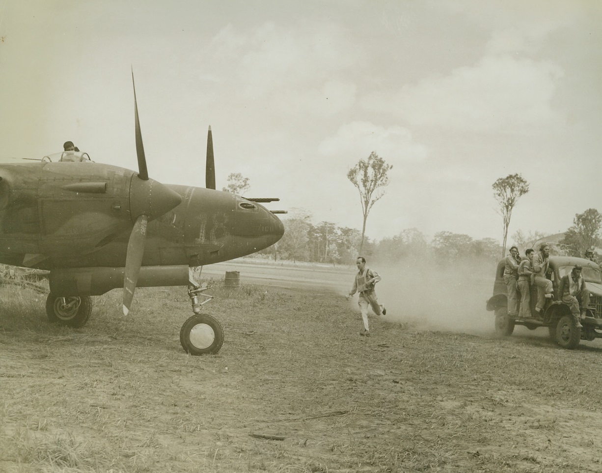 Quick Delivery, 1/10/1943. Port Moresby, New Guinea – A new fighter group with their speedy P-38’s are now on the job at Port Moresby.  Here a truck brings an American P-38 pilot to his plane, where a mechanic is all ready to start the motors.  The pilot rushes up to be set for the takeoff. Credit line (ACME);