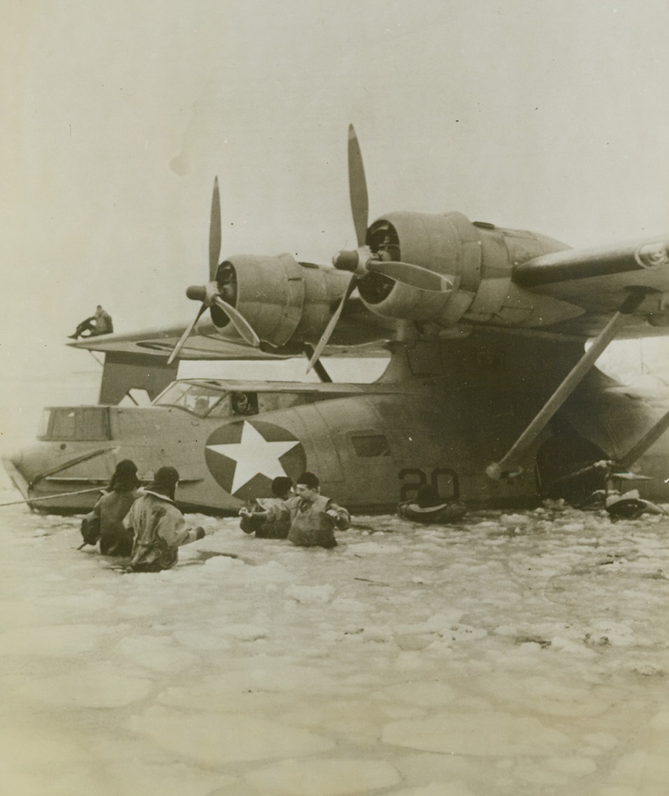 Cold Weather For Wading, 1/10/1943. Alaska – This big PBY patrol bomber is being maneuvered toward land in the icy Northern Pacific waters by a Navy ground crew.  Tough going, but nothing seems to stop a ground crew. Credit (official US Navy photo from ACME);