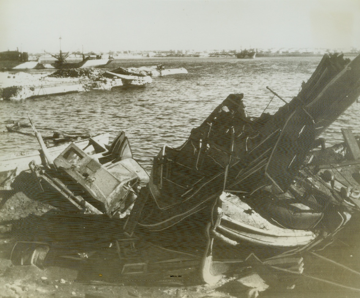 Tripoli Harbor, 1/27/1943. Tripoli – As General Montgomery’s triumphant 8th Army marched into Tripoli, they saw the damage Allied bombers had done to that city’s harbor, pounding relentlessly from the air at the axis-held harbor. Credit line (ACME radio photo);