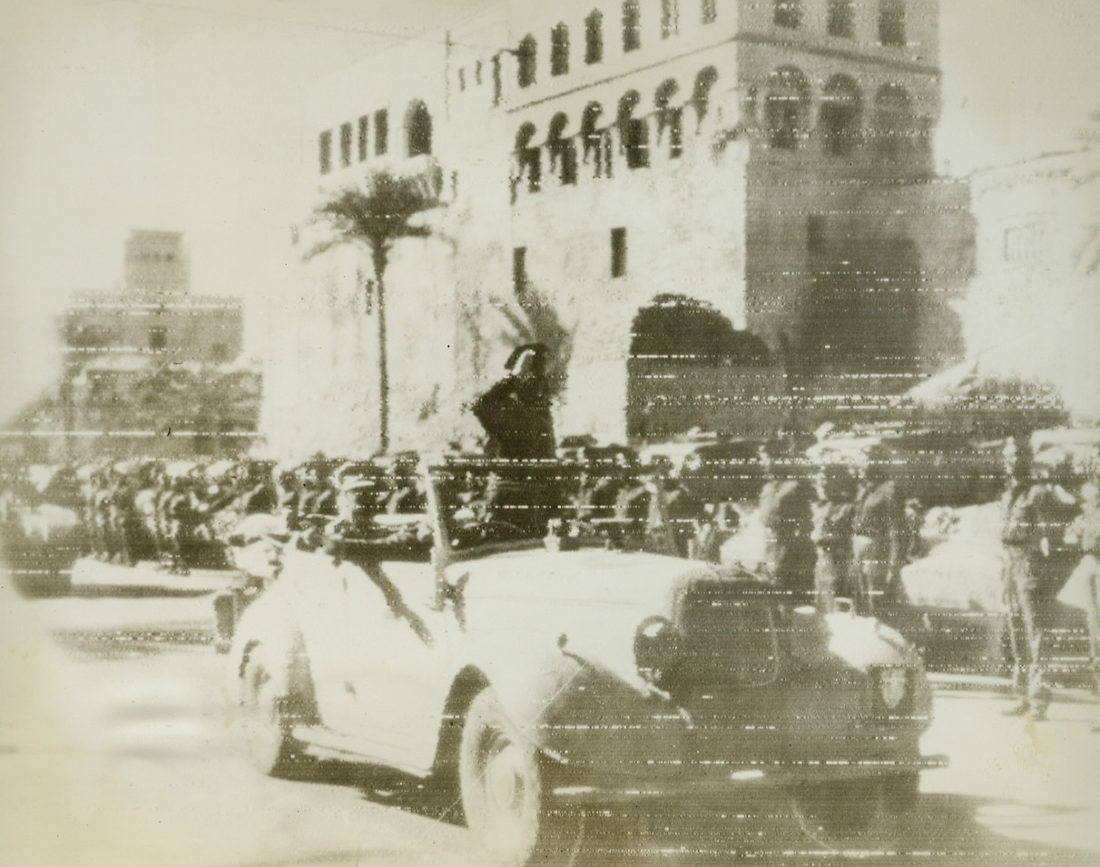 First Photos of Tripoli’s Fall, 1/25/1943. Tripoli—General Bernard L. Montgomery, commanding the British Eighth Army, stands up in the rear seat of his car, to acknowledge the salute of men of the British tank corps after their triumphant entry Tripoli,  once proud center of Mussolini’s North African Empire. This photo, received by radio in New York today, was one of the first to be transmitted after Tripoli’s fall to the Allies. Passed by censors.Credit: ACME radiophoto.;