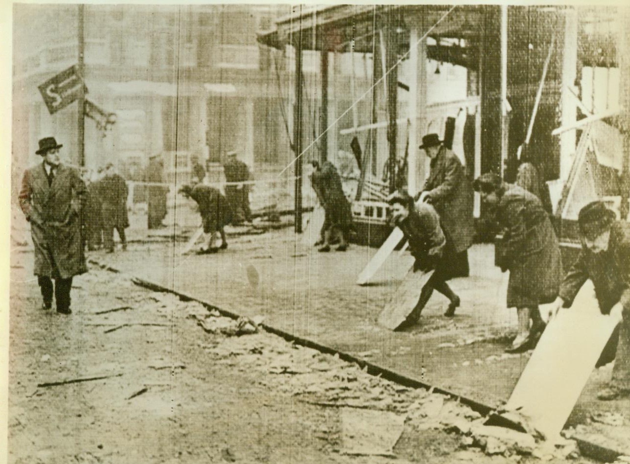 Girls Clear London Bomber Debris, 1/18/1943. LONDON - London girls sweep up shattered glass and the slight debris outside of a department store which was damaged during the feeble Nazi aerial atteck on January 17. The Nazis scarcely damaged the British Capital in their weak retaliation for the devastating RAF raids on Berlin.; Photo cabled from London to New York today.; Full DJH; Credit (ACME cablephoto); 1/18/43;