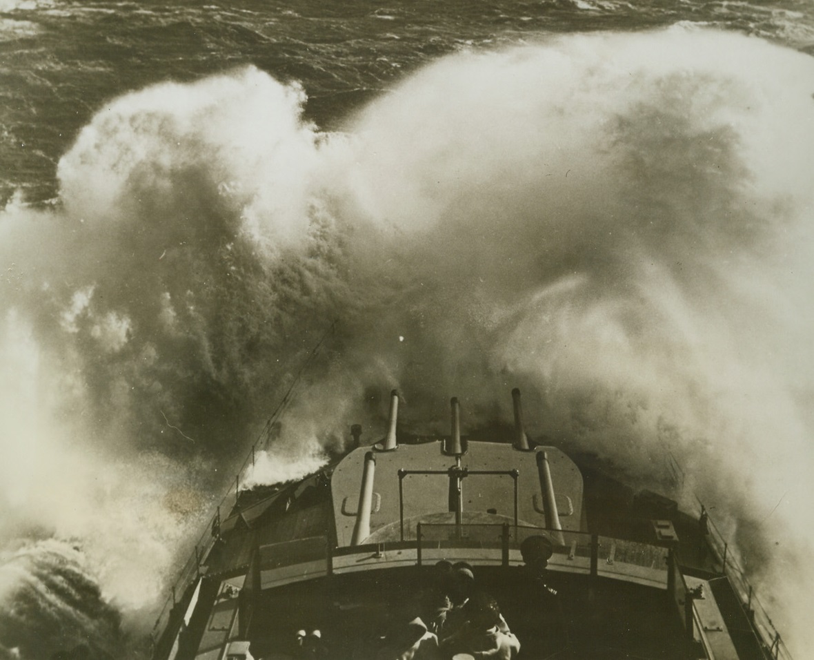 Bucks the Seas During Speed Test, 1/26/1943. In a bursting fountain of spray, a British Cruiser, repaired in a U.S. port under lend-lease, drives full speed ahead through heavy seas in a speed trial off the American Coast. The bow of the warship was almost entirely hidden by cascading salt water which threatened to engulf the entire forward structure. Officers checking the ship’s performance are on the bridge in the foreground. Credit: U.S. Navy official photo from ACME;