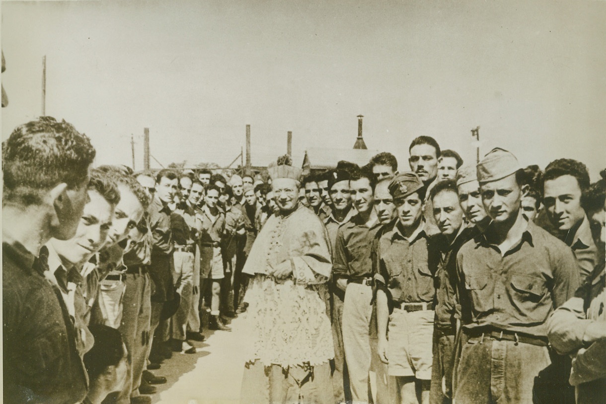 ARCHBISHOP VISITS PRISONERS OF WAR, 9/3/1943. WEINGARTEN, MO – The spiritual needs of prisoners of war interned in camps in America are not overlooked. Archbishop Amleto Giovanni Cicognani, Papal Representative to the U. S., is shown with a group of Italian prisoners during his recent visit to the PW camp at Weingarten. His Excellency celebrated mass and distributed gifts of prayer books, rosaries and similar articles. Credit: Official U. S. Army photo from ACME;