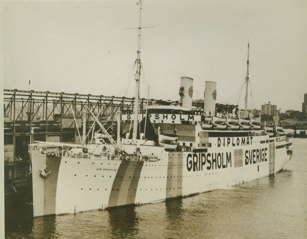 SAFE ON THE HIGH SEAS, 9/3/1943. NEW YORK CITY – In contrast to the drab vessels of war, the Swedish exchange liner “Gripsholm” sports the brilliant blue and gold colors of her country on her side, with her name and the word “Diplomat” prominently lettered between the colors. At night, while on the high seas, she will be gaily lighted to reveal her identity. Guaranteed safe conduct by all belligerent governments, the liner will voyage to the Far East, bringing relief packages from the U. S. to American prisoners of war. She will return with non-military internees. The Gripsholm is shown in New York harbor. Credit: Official U. S. Navy photo from ACME;