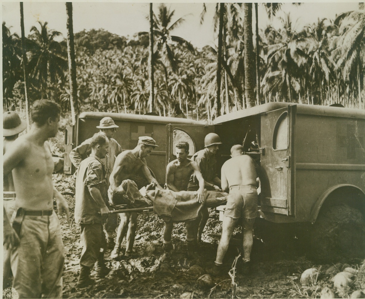 Removing New Georgia Wounded, 9/21/1943. NEW GEORGIA ISLAND – Allied wounded are placed in ambulances for removal from the fighting zone on New Georgia Island. Note mud-caked wheel of ambulance in foreground. The Japs have been driven from Munda Point on New Georgia after bloody fighting and only isolated pockets of resistance remain. Credit: U.S. Signal Corps photo from ACME;