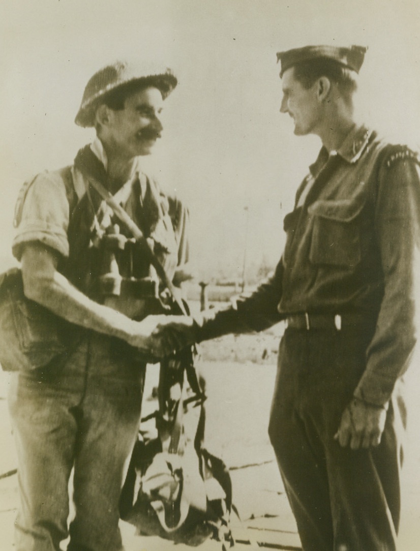 GOOD LUCK, PAL, 9/10/1943. SICILY—An American Ranger shakes hands with a British Commando, just before the two specialist fighters leave a Sicilian port and set out for Italy. Each of these Allied soldiers knows what the other is up against, for both do the same sort of rough-and-tumble fighting.Credit: Acme photo via U.S. Army Signal Corps radiotelephoto;