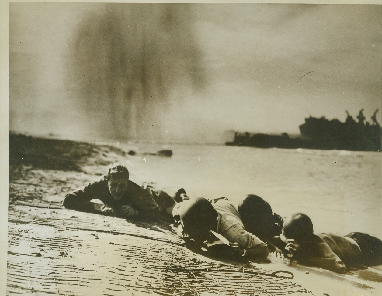 Hit the Dirt, Sailor!, 9/23/1943. Paesternum, Italy – U.S. Coast Guardsmen and Navy beach battalion men hug the beach as a Nazi bomber dumps its load near them at Paesternum, south of Salerno, during the bloody fighting in that area. In the background, (top center in photo), a cloud of black smoke from a bomb explosion hangs in the air. Hey, Sailor, keep that head down! Credit: (U.S. Coast Guard Photo from ACME);