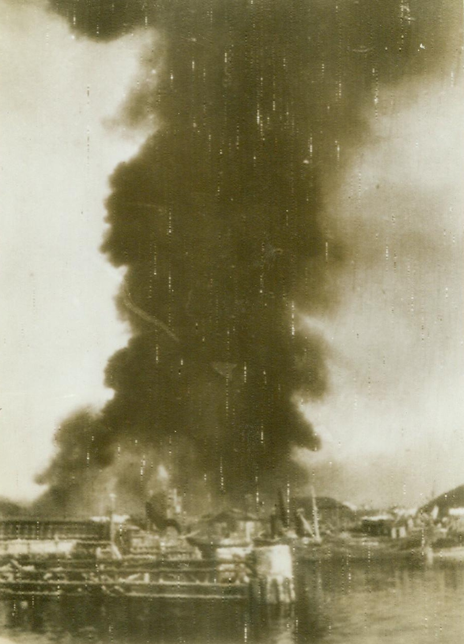 ALLIES SMACK TRONDHEIM, 9/14/1943. New York: -- Black smoke billows skyward from a blazing German oiltank three minutes after the first bomb dropped on Trondheim’s “new harbor” during a big Allied day raid on the Norwegian port on July 24. Photo was radioed from Stockholm to New York Today (Sept. 14). Credit (ACME Radiophoto);