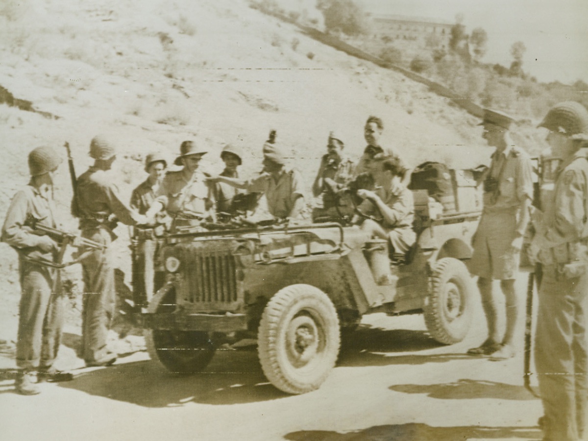 As 5th and 8th Armies Met in Italy (#2), 9/22/1943. Italy—This alert U.S. 5th Army Platoon, (in foreground), took no chances when they sighted cars filled with what appeared to be British soldiers driving toward them along this road in Italy. They blocked the road, their guns ready, and stopped the strangers only to find they were an advanced patrol of the British 8th Army which had driven from the south of Italy to meet the American forces in the Salerno area, the two groups exchange greetings. (Also see ACME photo #RW698606). Credit: U.S. Signal Corps radiotelephoto from ACME.;