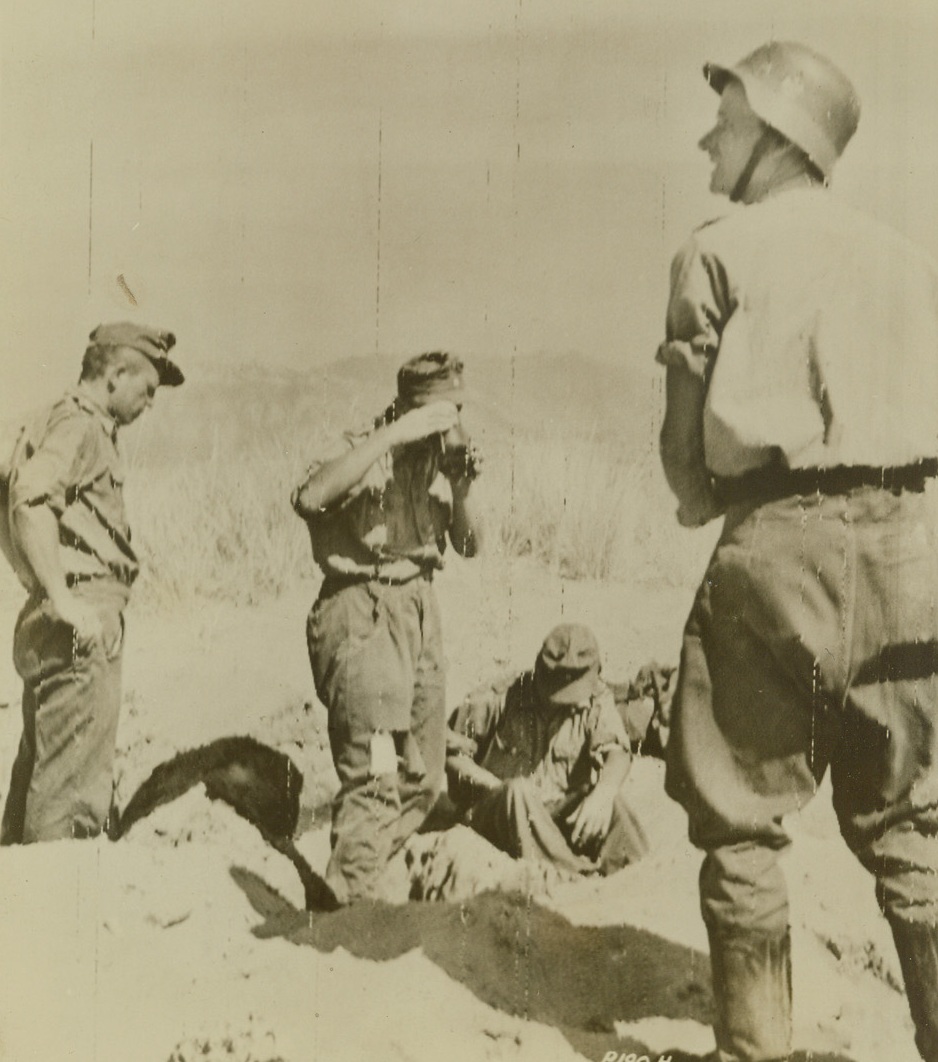 Defense Against their Own Planes, 9/17/1943. ITALY—After losing their first encounter with American troops on Allied soil and being taken prisoner; these crestfallen Nazi soldiers dig foxholes to protect themselves from bombing and strafing by their own planes. One Nazi takes a drink from his canteen before digging in. Credit: SIGNAL CORPS RADIOTELEPHOTO FROM ACME.;