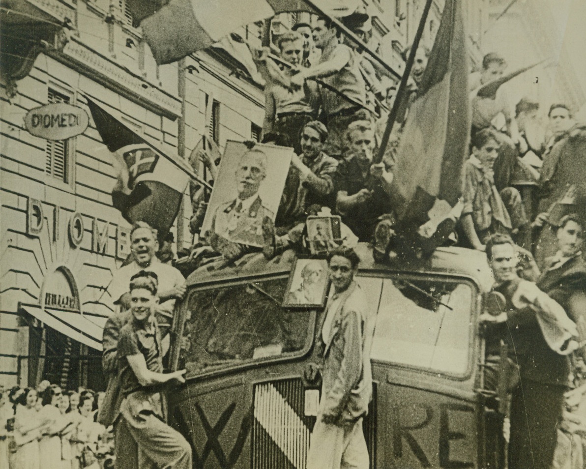 Demonstrators on a Bus, 9/17/1943. ROME—Italians, celebrating the downfall of Mussolini on July 25th, clamber atop the roof and the front of a bus in the streets of Rome to wave Italian flags, pictures of King Victor Emmanuel, and shout their approval of the capitulation of Le Duce. This photo is from an Italian newsreel obtained through a neutral source. Credit: ACME.;