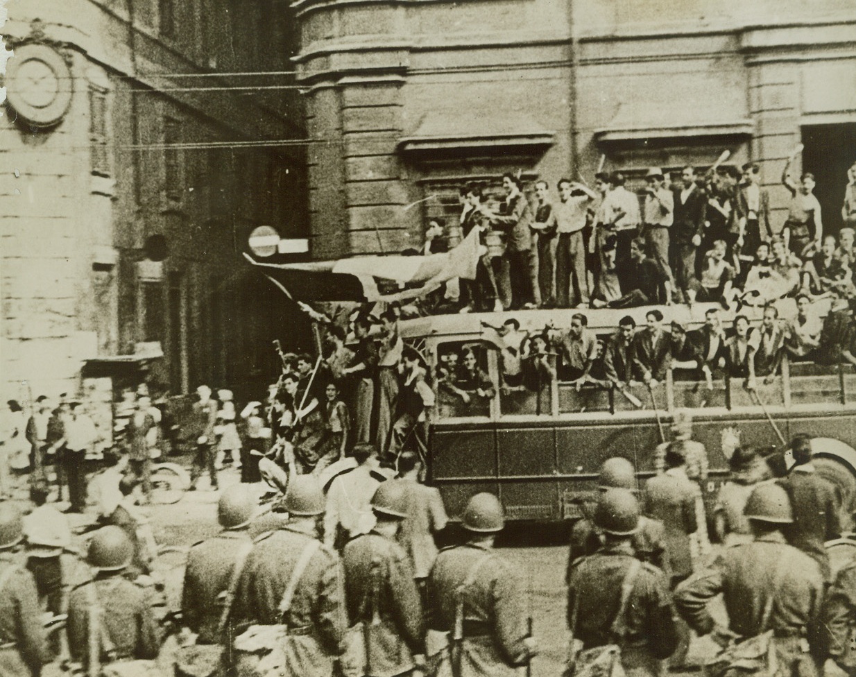 Glad to Be Rid of Benito, 9/17/1943. ROME—Turning out into the streets of Rome to shout their approval of the ousting of Benito Mussolini, these happy Italians jam a bus and climb to the roof of the vehicle to celebrate. Italian soldiers look on as the liberated Italians demonstrate. This photo if from an Italian newsreel, obtained through a neutral source. Credit: ACME.;