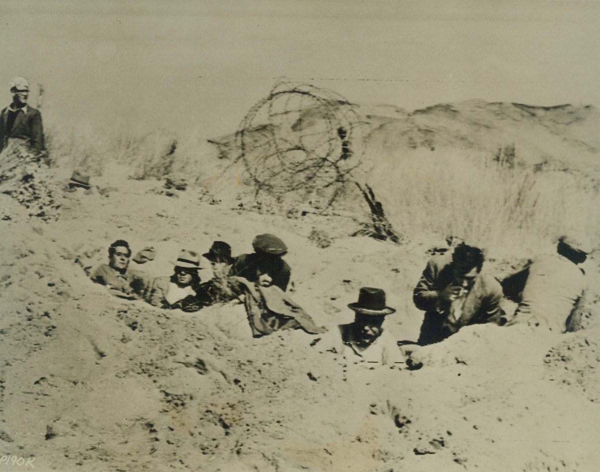 Italians Dig In, 9/17/1943. ITALY—American troops, invading the Italian mainland, came upon this group of Civilians on one of the beaches. Crouching in hastily-dug foxholes, the men sought safety from bombing and strafing attacks by their own planes. Credit: SIGNAL CORPSS RADIOTELEPHOTO from ACME.;