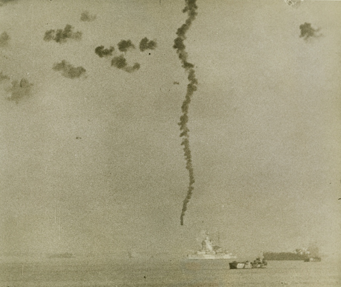 NAZI SKY-WRITING, 9/30/1943. SALERNO, ITALY—Our anti-aircraft is on the job as American landing forces approach Salerno, Italy, and an enemy plane trails a dark plume of smoke as it hits the water. On land, Nazi shore batteries keep up a constant barrage against the U.S. troops storming ashore. Credit: Newsreel pool photo from Acme;