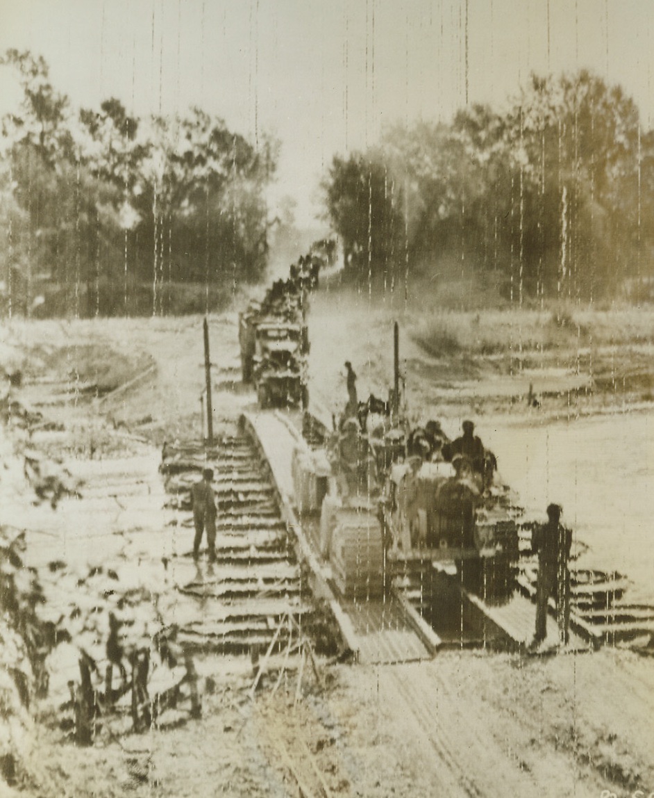 GUNS TRAVEL TO THE FRONT, 9/26/1943. ITALY—Drawn by tractors, these big guns cross a bridge, built by American Army engineers, as they head for the Italian fighting front. Credit: Signal Corps Radiotelephoto from Acme;