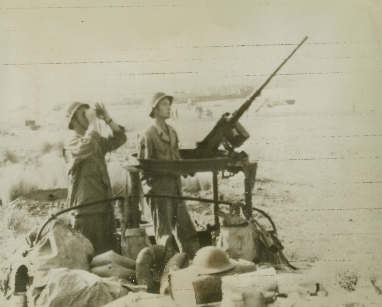 WATCH ON A “DUCK”, 9/15/1943. SALERNO, ITALY—Scanning the skies for enemy planes, these Yanks stand watch with a heavy anti-aircraft machine gun mounted atop an amphibious, 2-1/2-ton “duck” on a beach in the Salerno area. Photo radioed to New York from Algiers today (Sept. 15th). Credit: Official OWI radiophoto from Acme;