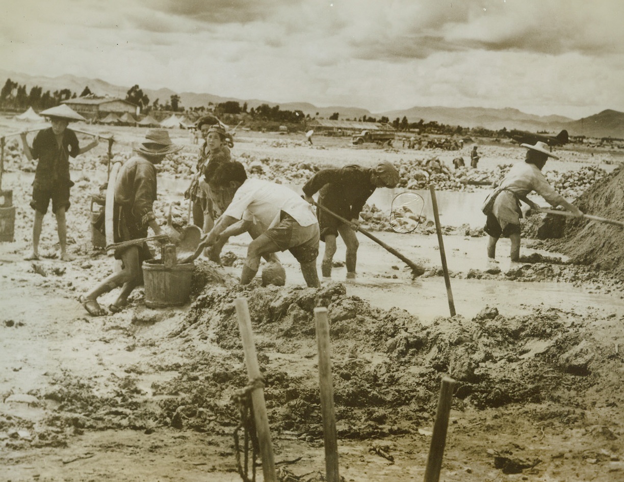 Building A Field For “Iron Birds”, 9/29/1943. Somewhere In China – Working with ancient tools and with the indomitable will and spirit that has gained the respect of the world for the people of China. These natives mix mud and water which will bind bricks together for an Air field “Somewhere in China.”  9/29/43 Credit Line (U.S. Army Air Forces Photo From ACME);