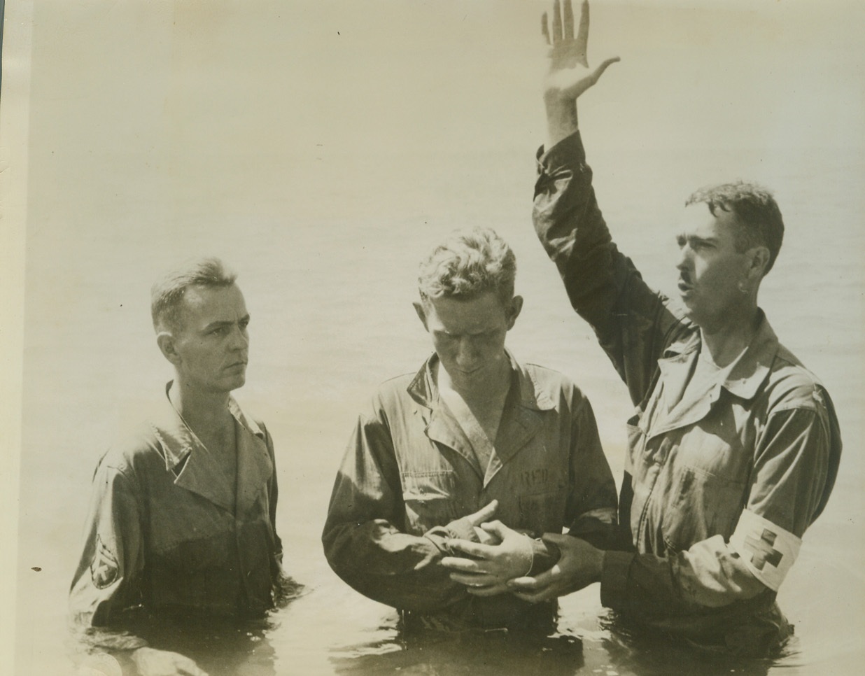 Americans Baptized in Mediterranean, 9/27/1943. SAN AGATA, SICILY -- This photo, taken on the occasion of the first baptism in the Mediterranean Sea conducted by Chaplain Harvey Floyd Bell, (right), from Greshamville, Ga., was taken off the north shore of Sicily 15 miles east of San Agata. Chaplain Bell, who is attached to an American infantry unit and who is of the Baptist-South Church, is shown baptizing Pvt. John Davis, (center), of Harrisonburg, Va. Credit: (U.S. Signal Corps Photo from ACME);
