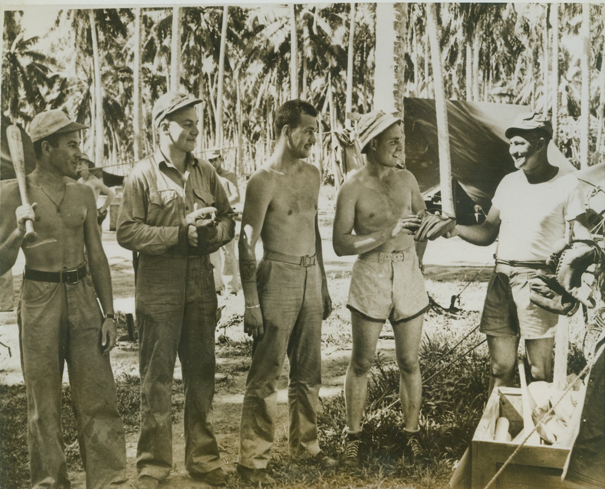 Time Out for Baseball, 9/24/1943. SOMEWHERE IN THE SOUTH PACIFIC -- In spite of tropical discomforts and the dangers of war, our Leathernecks always manage to find some time for a fast baseball game. Here, as the boys get ready for a game in a coconut grove, Marine Corps Chaplain, the Rev. Balthasar V. Schomer, of Council Bluffs, Ia., hands out equipment to (left to right) Sgt. Charles W. Speakman of Meadville, Pa.; Cpl. Albert G. Fissel, Newport, Ky.; Cpl. Edward S. Kowalski of Poughkeepsie, NY; and Tech. Sgt. Lawrence G. Fischer of New Orleans, La. Credit: (U.S. Marine Corps Photo From ACME);