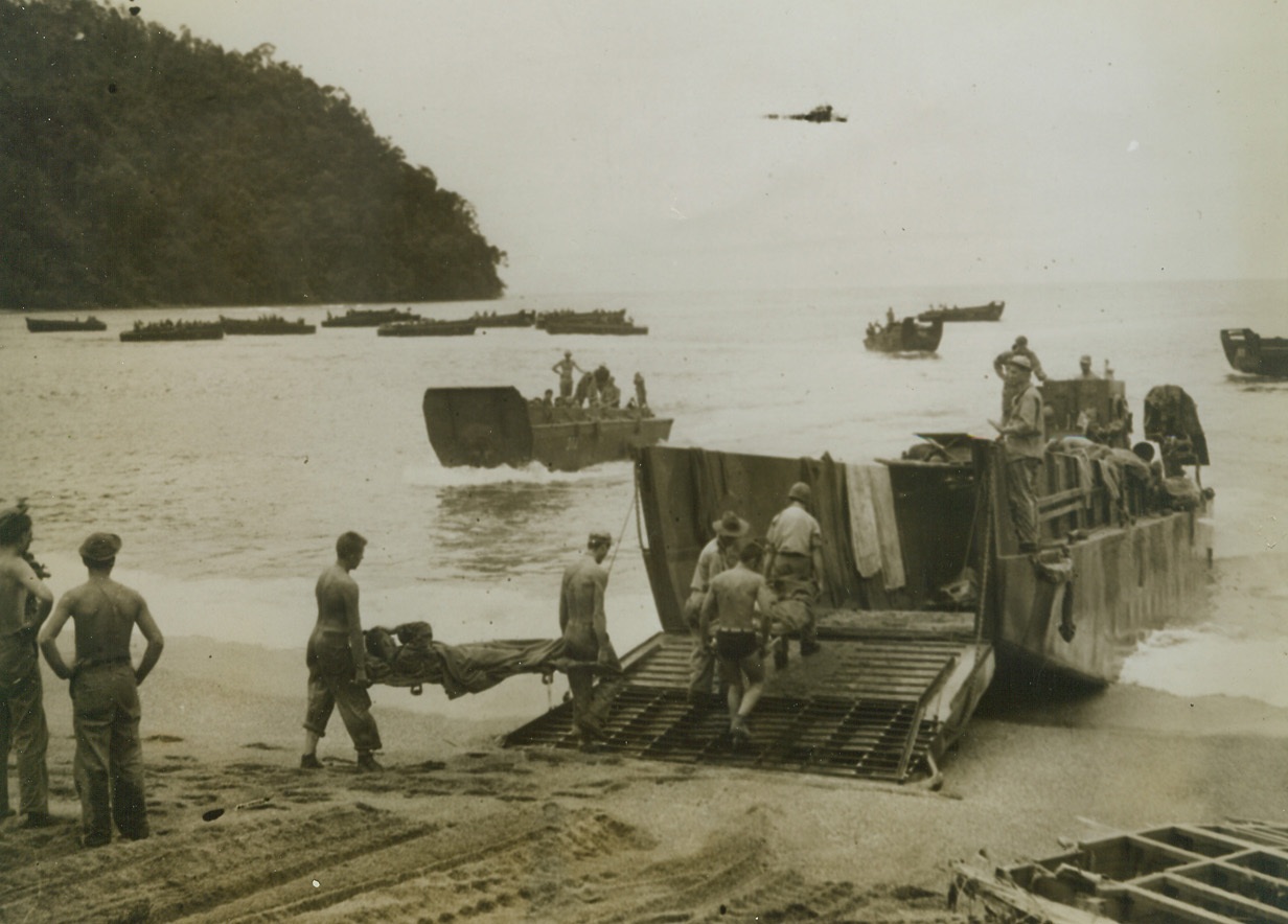 Victims of Jap Bullets, 9/12/1943. New Guinea – American soldiers who were wounded on the Salamaua front in New Guinea are loaded in barges on a nearby beach, and are on their way to a hospital.  The announcement of the fall of the Jap stronghold at Salamaua is expected almost momentarily, and this photo shows part of the price of victory.Credit Line (ACME);