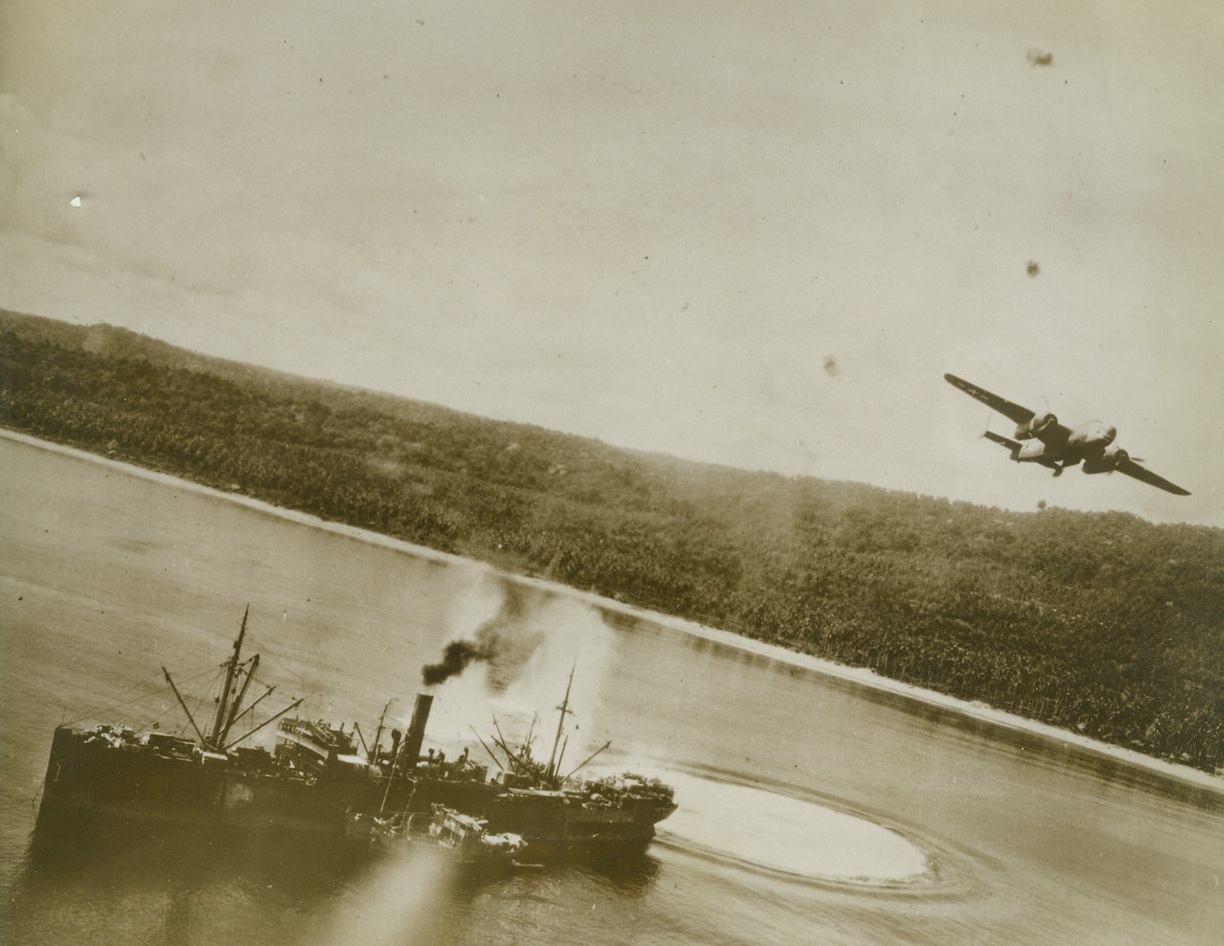 NEAR-MISS ON A NIP, 9/15/1943. This photo, just released by the War Department was taken from one of a group of U.S. Fifth Air Force bombers, during a recent low-level attack on Wewak Harbor, important supply base in New Guinea for Salamaua and Lae. Jap ship, (in foreground), has just been shaken by bombs exploding, (white circles astern), in the water. At the right, one of the Yank bombers, flying through the black puffs of heavy anti-aircraft fire, has just dropped its load of bombs. The small boats tied alongside the freighter are lighters. Today, Salamaua is in the hands of the Allies, who are only two miles from the center of the Jap base at Lae.  Credit: U.S. ARMY AIR FORCES PHOTO FROM ACME.;