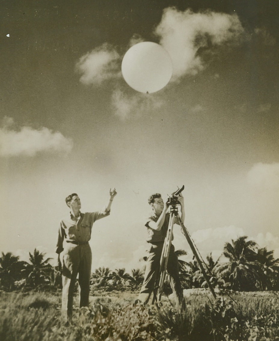 TESTING WINDS, 9/16/1943. CENTRAL PACIFIC—Two Seventh Air Force weathermen, stationed at an island air field in the Central Pacific, release a hydrogen-filled balloon to test winds. Sending the balloon aloft are: Cpl. William H. Allen (left) of Jasper, Texas, and Pfc. Howard C. Luke of Long Island, NY.Credit: ACME;
