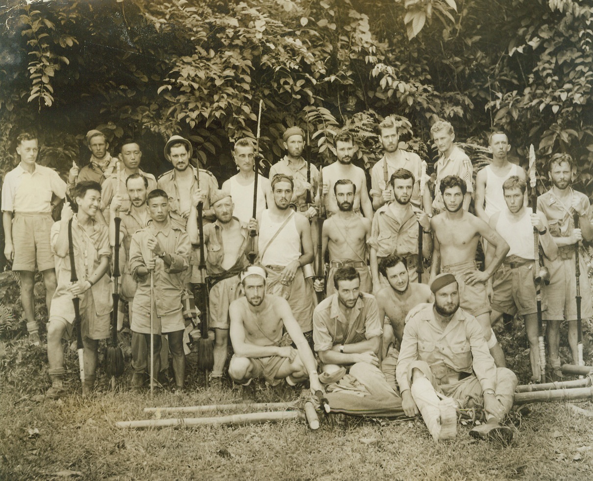 Out of the Jungle, 9/28/1943. India: - The twenty survivors of an ATC plane which crashed in Northern Burma, who participated in a dramatic mass parachute jump to safety when the ship developed engine trouble, August 2, while en route to China from India, are shown with members of a parachuting rescue party upon reaching the safety of India once again.  The complement marched 26 days through dense jungle growth in an area laden with head-hunters.  Left to right, back row: Philip Adams, British sub divisional officer, of ground rescue party; Sgt. E. Wilder, Levelland, Tex.; Col. Wang Pao Chao, Chinese officer; Eric Sevareid, CBS news commentator; William T. Stanton, of Board of Economic Warfare; Sgt.  Joseph E. Clay, Monticello, Ia.; Cpl. Basil M. Lemon, Tulsa, Okla.; Sgt. Glen A. Kittleson, Ballantine, Mont.; Sgt. Francis W. Signor, Yonkers, N.Y., and Cpl. Lloyd J. Sherrill, Burlington, Ia. Middle row:- Lt. Roland K. Lee, Hicksville, Long Island, N.Y.; Lt. Col. Kweh Li, Chinese Army; John Davies, of State Department; Sgt. Ned C. Miller (crew chief), Ottumwa, Ia.; Flight officer Harry K. Neveu, pilot of the ship, Cudahy, Wisc.; Sgt. Joseph J. Gigore, Auburn, Mich., (first name etc is illegible) Schrandt, Philadelphia, Pa.; Cpl. Edward Holland, Cleveland, Ohio; Cpt. S. Waterbury, Blue Hill, Nebr.; Capt. D.C. Lee, Haddon, Ia., of adjutant General’s office.  Kneeling, Sgt. Richard Passey, Provo, Utah, Lt. Col. Don D. Flickinger, ATC flight surgeon, and Cpl. William G. McKenzie, Detroit, Mich., the trio who jumped from rescue plane to aid crash victims.  In front on stretcher is Sgt. Walter R. Oswalt (radio operator), of Ansonia, Ohio, who broke a leg when he parachuted from stricken plane.  He was carried for 26 days by natives before reaching civilization.  Credit (photo by Frank Cancellare, War Pool photographer, from ACME;