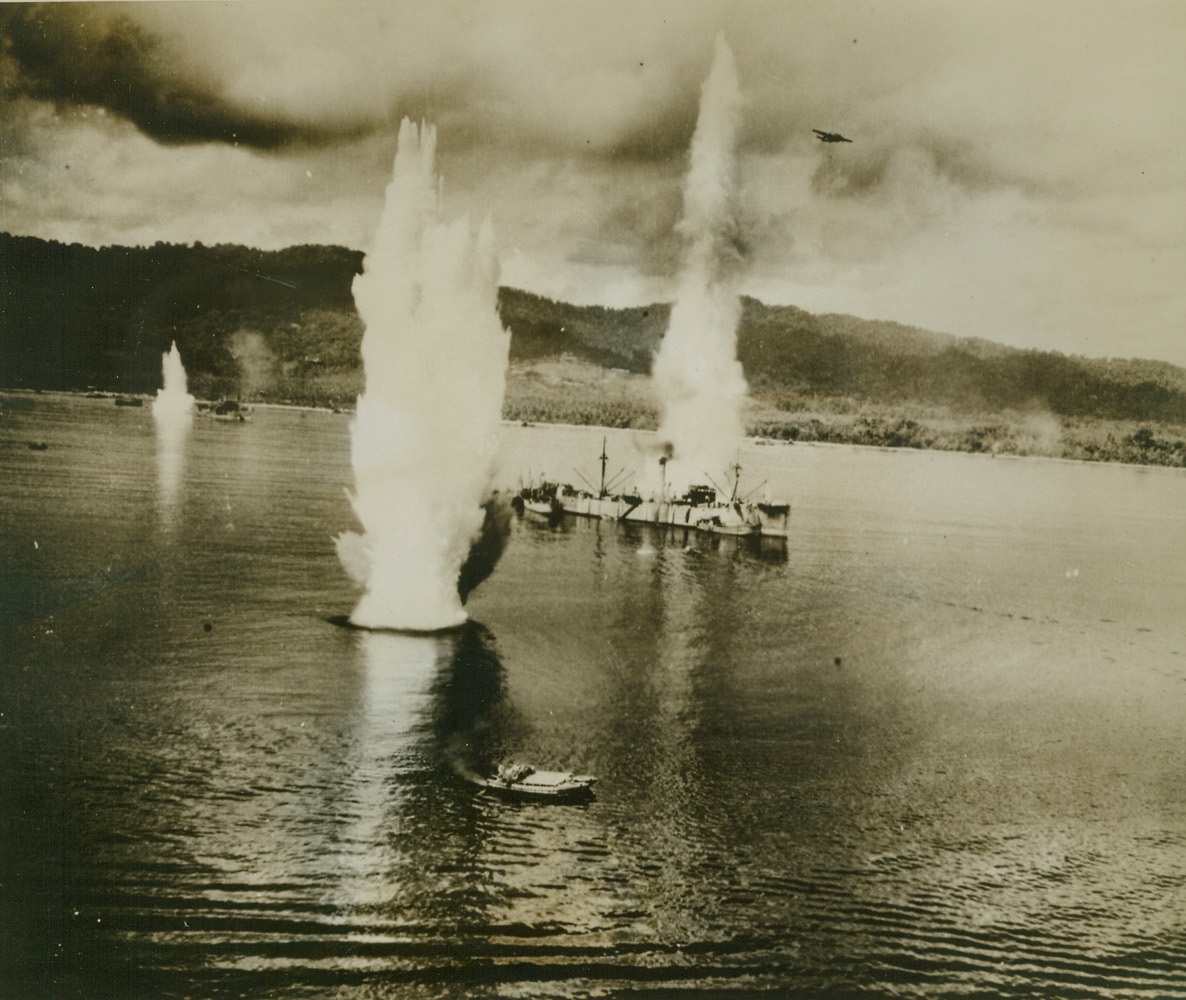 Yank “Eggs” for Nip Ships, 9/15/1943. This photo, just release by the War department, shows giant geysers from exploding American bombs near Japanese ships anchored in Wewak Harbor during a recent low altitude attack by U.S. bombers, (one can be seen, top right), on the important New Guinea supply base for Lae and Salamaua.  The small lighter, (foreground), tries to zigzag out of harm’s way.  Today, the allies are in possession of Salamaua and are within two miles of the center of Lae. Credit line U.S. Army Air Forces photo from ACME;