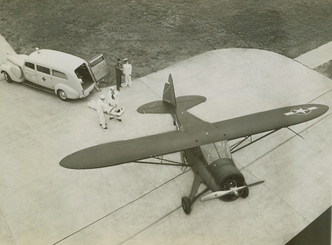 Rehearsal for Mercy, 9/12/1943. Chicago—Navy men from Chicago try out the new naval hospital ship, the Howard Nightingale, first of a new type of swift, maneuverable plane being turned out to transport badly wounded men from battle fronts to hospitals behind the lines. The plane holds two wire basket-type stretchers, one above the other, in a rigid position so that manipulation of the plane while dodging possible enemy pursuit will not further injure the patients. Naval officials and the Howard Aircraft Company, manufacturers of the ship, are dedicating it to Florence Nightingale. Photo No. 1 shows a stretcher being carried from an ambulance to the plane. (passed for publication)Credit: ACME.; v