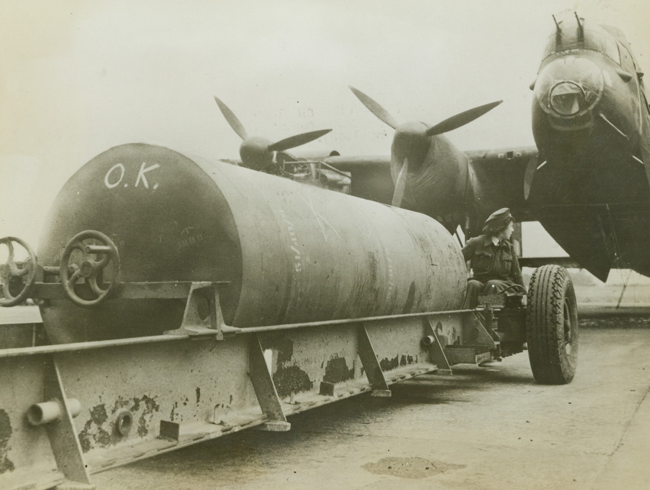 O.K., RAF, Take ‘Er Away, 9/20/1943. Somewhere in England – This big baby, which tips the scales at 8,000 pounds and makes a mess of enemy targets when it falls, is very much of “O.K.” The giant missile is backed up in front of the RAF Lancaster bomber that will soon carry it away on a night raid over Axis territory. Credit: ACME;