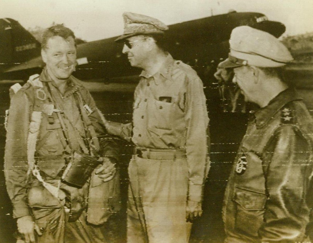 Bids "Good Luck" To Paratrooper, 9/7/1943. Gen. Douglas MacArthur, (center), wishes Paratrooper Lt. Col. J.J. Tolson, (left), of New Bern, N.C., good luck just before the Paratroopers took off to land in the Lae area of New Guinea, in this Radiotelephoto flashed to the United States today. Looking on at this Allied base “somewhere in The Southwest Pacific”, is Lt. Gen. George J. Kenny. 9/7/43 (ACME);