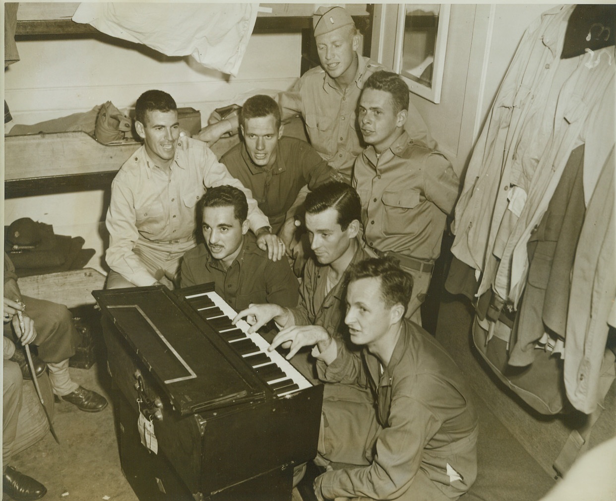 HARMONY BELOW DECKS, 10/27/1943. AT SEA – The boys are giving their version of Pistol Packin’s Mama aboard a troop transport bound for a South Pacific port. Left to right, standing: Lieutenants J. R. Ryan, Los Angeles, Calif.; N. W. Alexander, Dallas, Tex.; C. H. Parks, Oklahoma City, Okla.; W. E. O’Donovan, Baltimore, MD. Front Row: A. G. Tsimpides, Birmingham, Ala.; J. L. McHenry, Boston, Mass.; and P. L. Gressman, Buffalo, N. Y. Credit: OWI Radiophoto by Thomas Shafer from ACME;