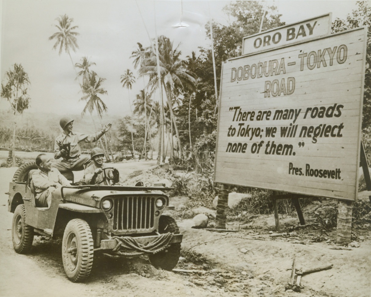 ONE ROAD TO TOKYO, 10/27/1943. ORO BAY, NEW GUINEA – This sign erected at Oro Bay, is a constant reminder to Allied troops there, that their goal is Tokyo. Left to right, are: “Little” Jack Little and Ray Bolger, stars who have been entertaining troops in the Southwest Pacific; and Col. C.S. Meyers, USA, who is driving the two around on a jeep sightseeing tour. Credit: U.S. Army photo via OWI Radiophoto from ACME;