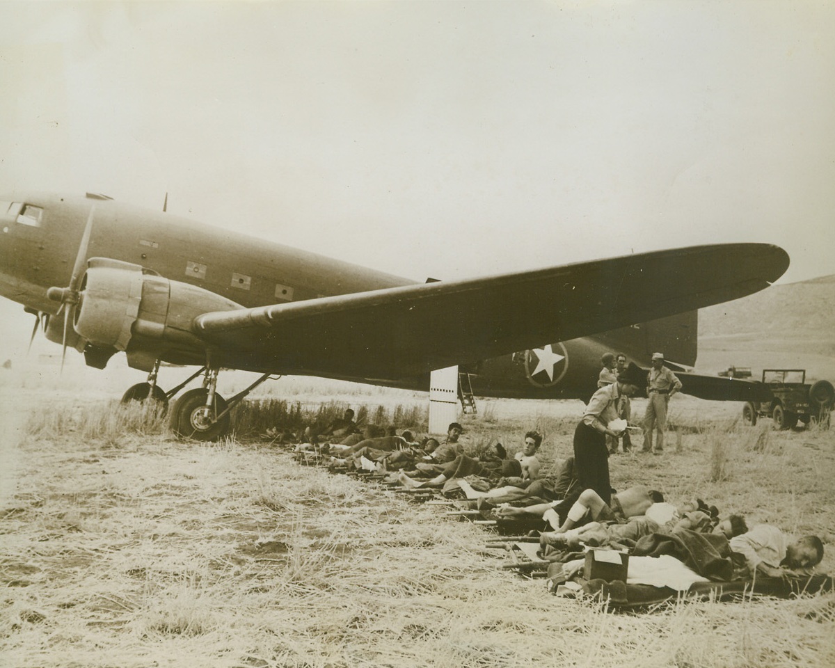 Ready For Air Hop to Hospital, 10/6/1943. Shaded from the burning sun, wounded Italian and Allied Soldiers wait to be put aboard this Douglas C-47 Sky Train transport plane and flown to a hospital in Africa.  A nurse tends to their needs as they rest beneath  the plane’s broad wing.Credit:  U. S. Signal Corps Photo from OWL NY DJH for #12 #17 AEP CEP CAN;