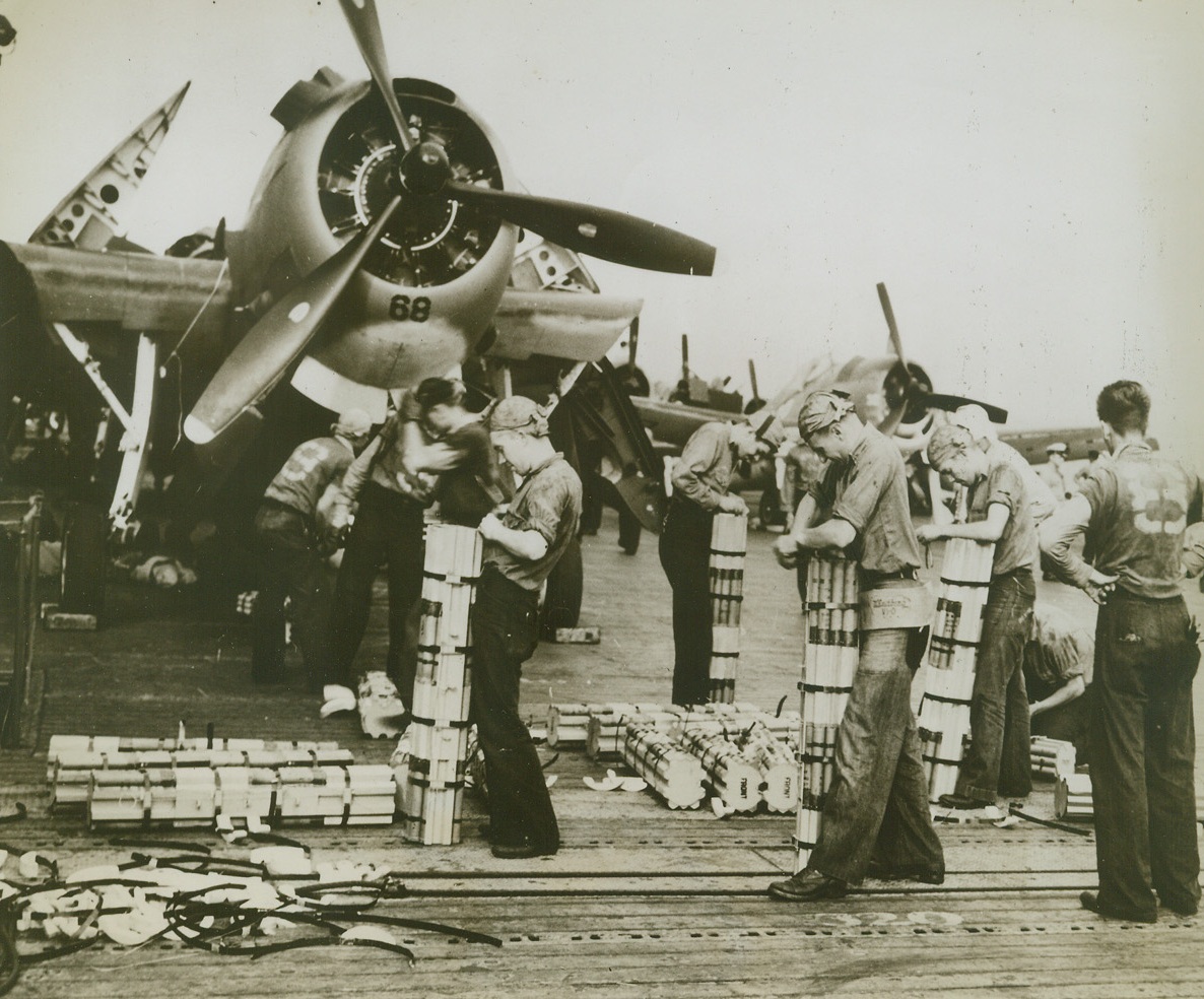 Firebugs, 10/16/1943. AT SEA – Crewmen aboard a Navy flat-top are shown preparing a rain of fire for the Jap defenders of Tarawa in the Gilbert Islands. They’re loading incendiary bombs on the planes in between the many raids of Sept. 18 and 19. “Zero hour” is at hand and the men are working together in perfect coordination.Credit Line (Official US Navy Photo from ACME);