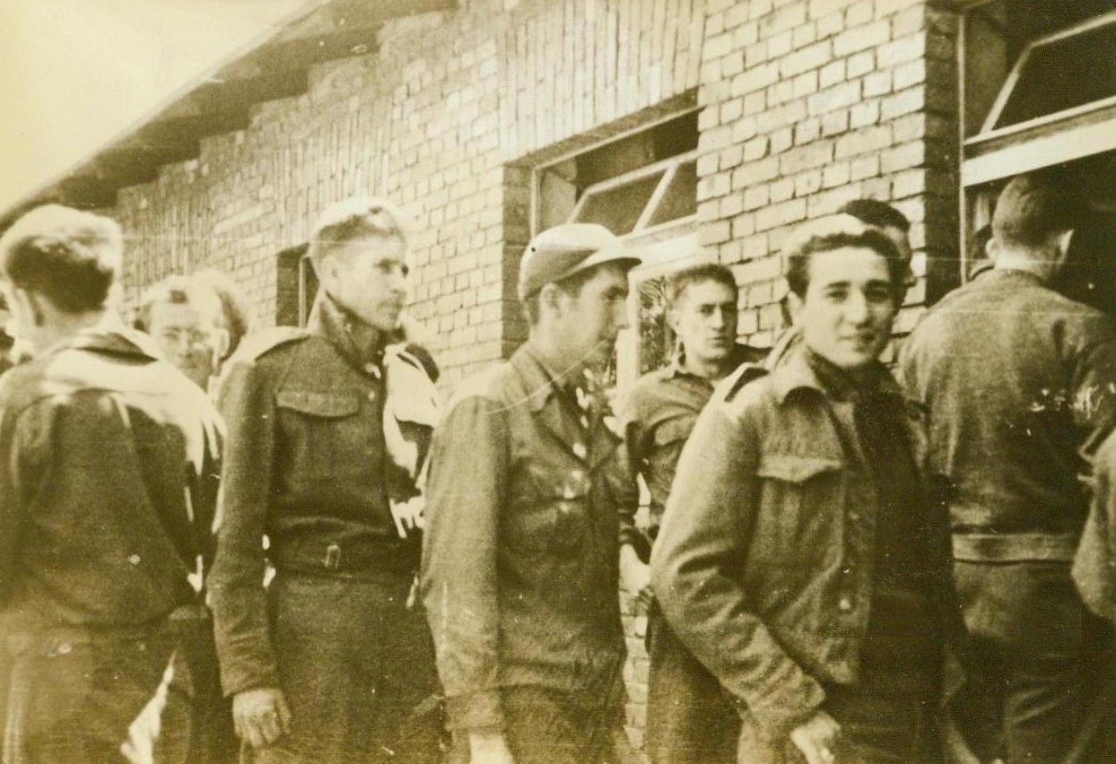 YANKS LINE UP FOR CHOW AT NAZI PRISON CAMP, 10/7/1943. This photo, sent to the United States by a Y.M.C.A. War Prisoners Aid delegate who visited the prison camp, shows American soldiers captured in the fighting in North Africa, as they lined up for chow at a mess hall at Stalag (Illegible), a camp southeast of Berlin. The delegate reported that the camp fare plus the weekly 11-pound food packages received from the American Red Cross, furnishes the interned Americans a better diet than that received by German civilians. In the photo, some of the men wear British uniforms as their own were probably damaged in battle. They will receive new U.S. uniforms soon. Credit Line (ACME);