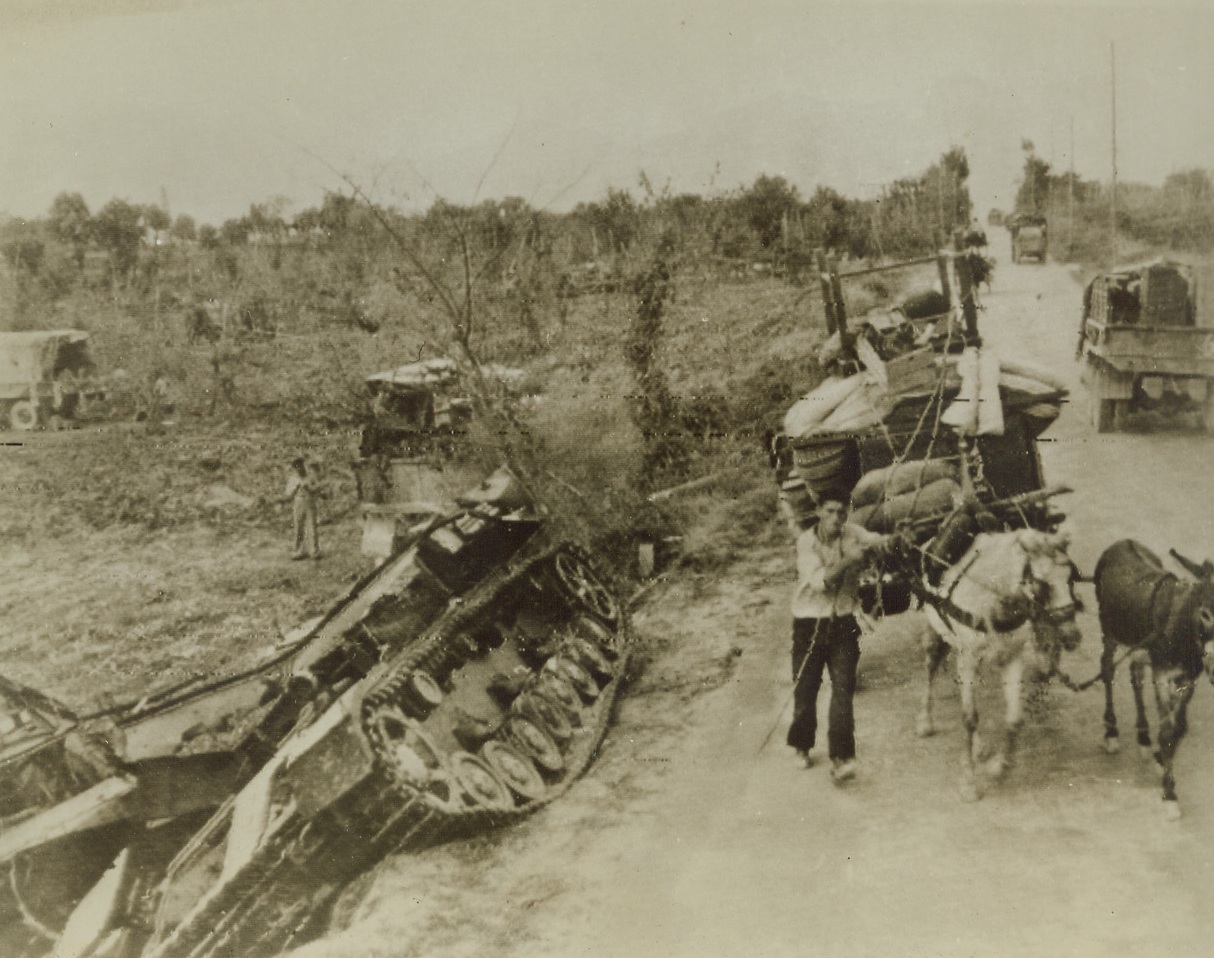 War Victims, 10/11/1943. NAPLES—Italian peasants are more interested in the problem presented by their household goods piled high on carts than they are the sight of a wrecked German tank on the road to Monte Corvine. These peasants have grown used to the sounds and violence of warfare and the problem of a new home are easily taken in stride.  Credit: ACME RADIOPHOTO.;